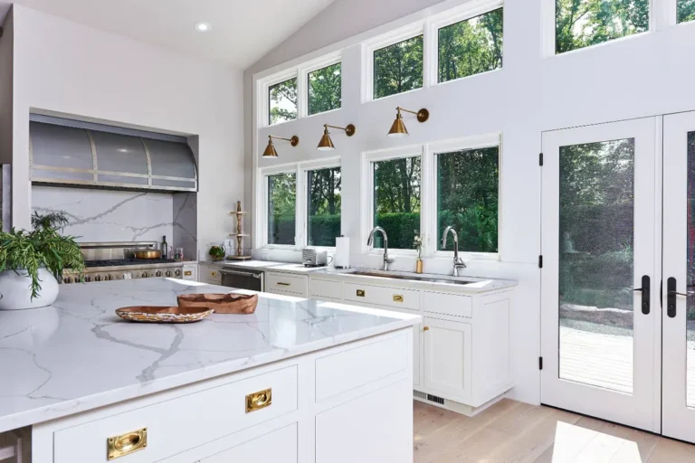 Белая кухня без навесных шкафов у стены с окнами в 2 яруса и выходом во двор дома