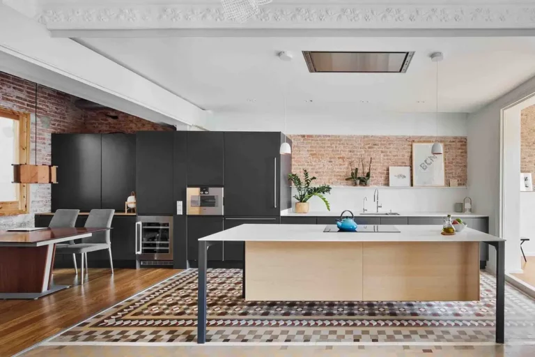 Черная кухня без навесных шкафов с кирпичной стеной, мозаичным полом и вытяжкой в потолке