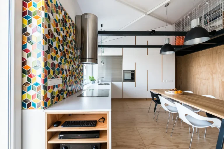 Древесно-белая кухня-гостиная с цветастой мозаичной стеной под высоким наклонным мансардным потолком