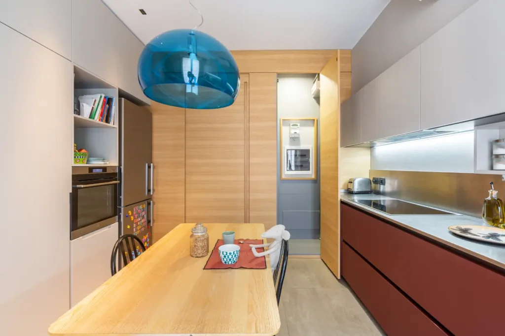 Кухня-модерн без ручек, соединенная с прихожей общим деревянным шкафом