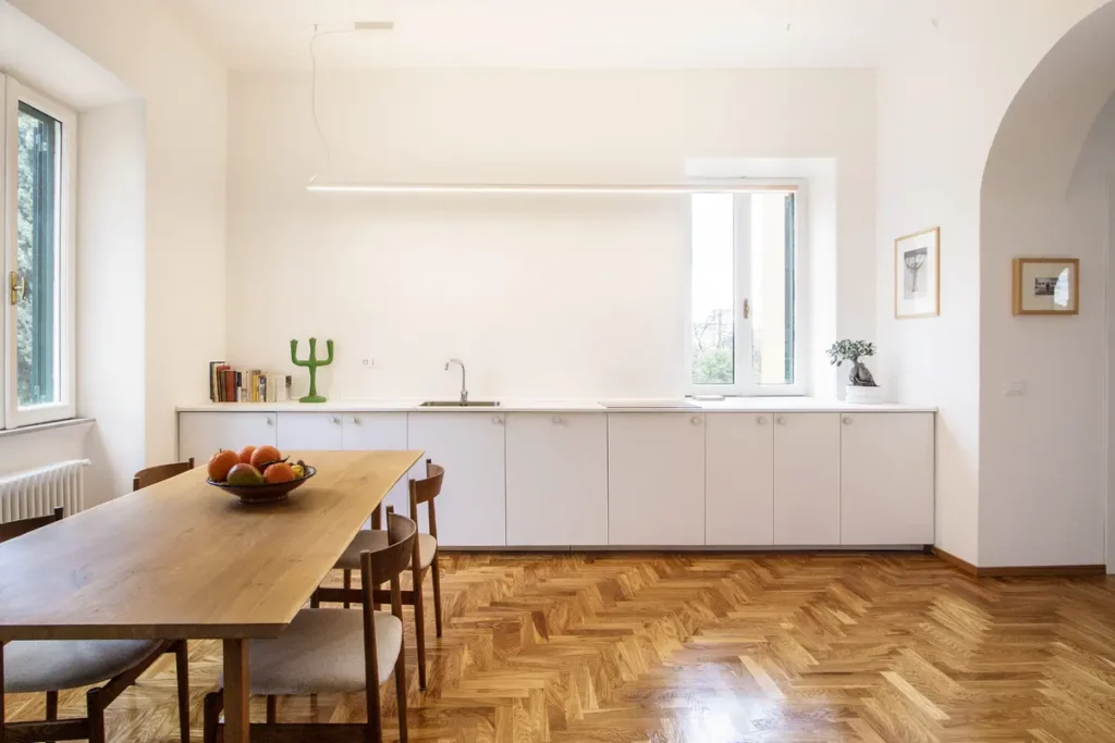 Минималистичная кухня с однотипными белыми фасадами и без навесных шкафов в скандинавском стиле