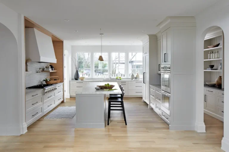 Современная кухня в скандинавских оттенках со стеной посреди помещения и буфетом позади нее