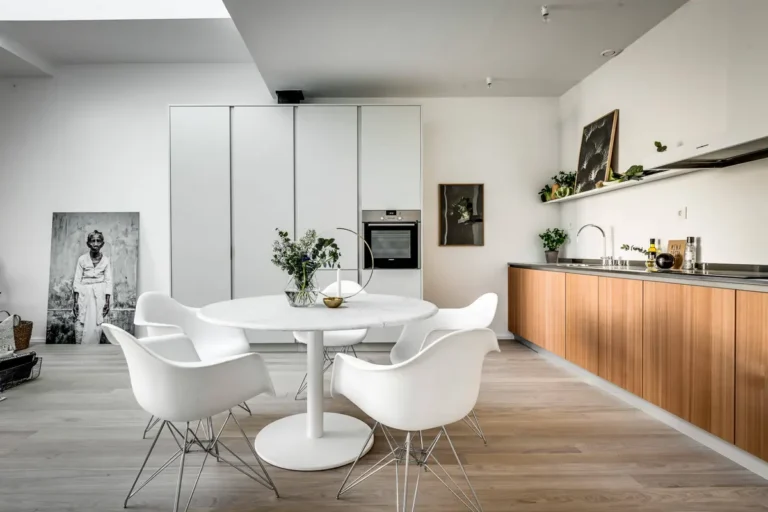 Современная скандинавская кухня-гостиная с деревянным гарнитуром, серым пеналом и зеленым диваном