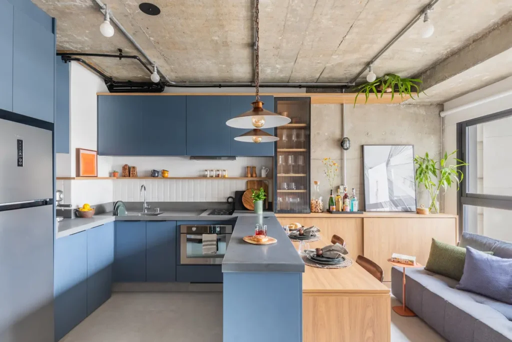 Универсальная кухня-гостиная-столовая с полуостровом в квартире-студии с бетонными стенами и потолком