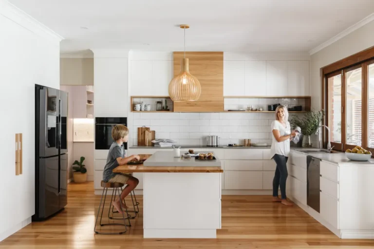 Дизайн большой белой встроенной кухни с деревянным полом, порталом и столешницей