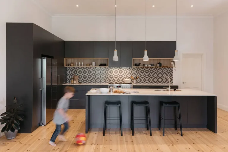 Интерьер светлой кухни с черным угловым гарнитуром и островом в стиле модерн